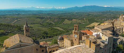 A historic town with traditional architecture, a prominent church tower, and a view of distant mountains.