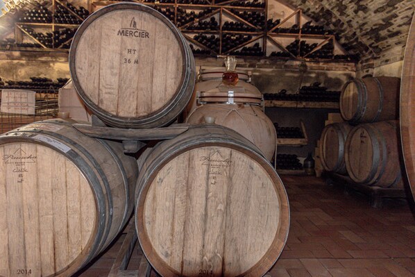 Wooden wine barrels stacked in a cellar with a wooden ceiling and walls. - Hotel Oviv Dimora del borgo (Acquaviva Picena)