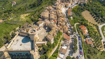 An aerial view of a historic town with narrow streets, a prominent church with a bell tower, and a castle-like structure with a circular courtyard.