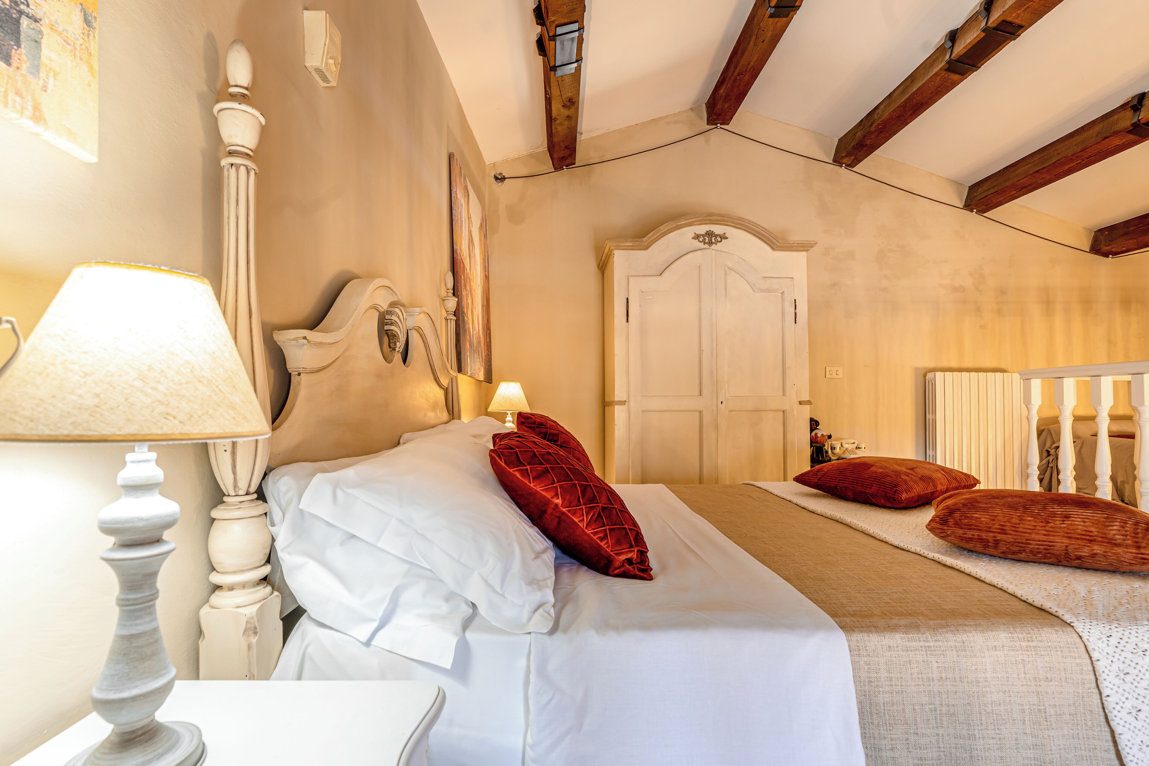 A bedroom with a bed, a nightstand, a lamp, a door, and a window.