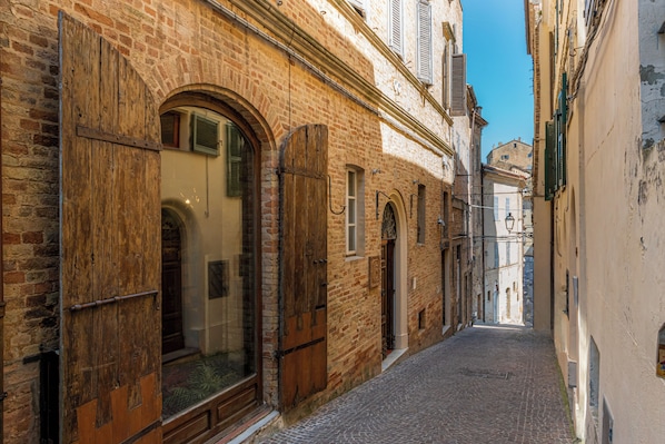 Eine enge Kopfsteinpflasterstraße mit historischen Gebäuden, hölzernen Fensterläden und blauem Himmel.
