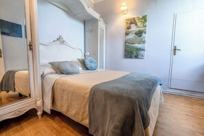 Une chambre à coucher avec un lit à baldaquin, un grand miroir, un tableau et une porte.