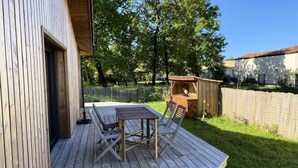 A wooden deck with a table and chairs, a small wooden structure, and a fenced yard. - House in Hourtin With Enclosed Garden (Hourtin)