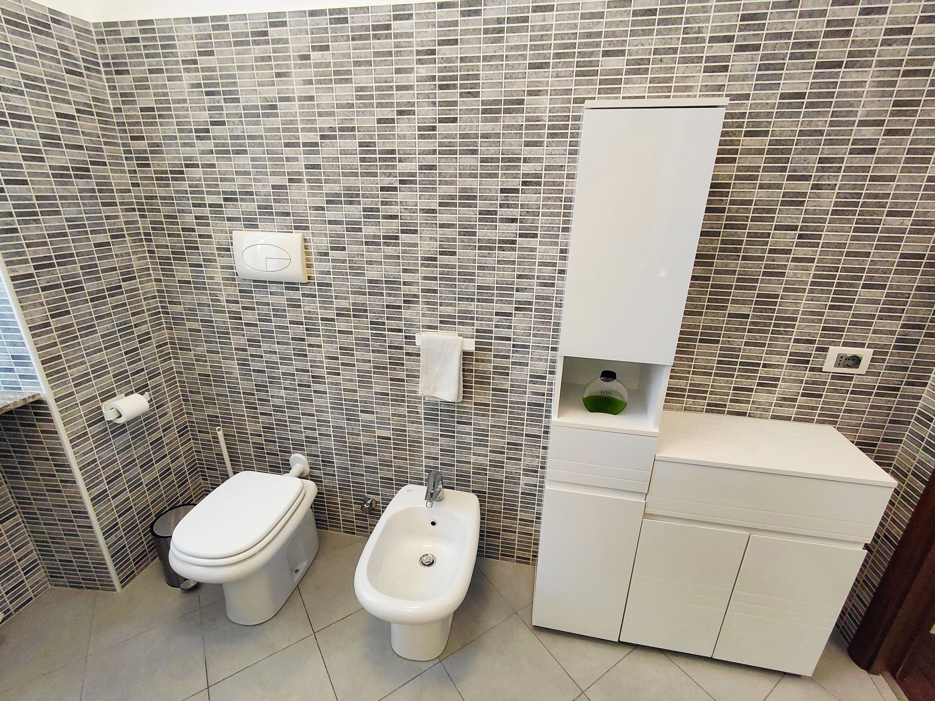 A bathroom with a toilet, bidet, and a sink with a mirror.