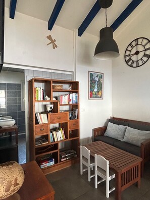 A cozy living room with a wooden bookshelf, a sofa, a table, and a clock on the wall.