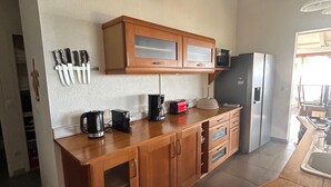 A kitchen with wooden cabinets, a countertop, and a refrigerator. - Villa with ocean views of the Cousteau Reserve and an infinity pool (Bouillante)