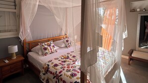 A bed with a canopy, a bedside table with a lamp, and a mirror on the wall. - Villa with ocean views of the Cousteau Reserve and an infinity pool (Bouillante)