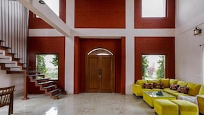 Un vaste espace de vie comprenant un escalier, une porte en bois et un ensemble de canapés jaune.