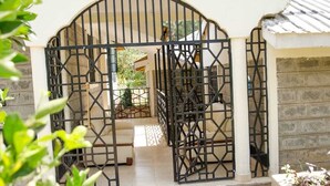 A gated entrance with a staircase leading to a covered area. - Everlasting Gardens Kitui (Kitui)