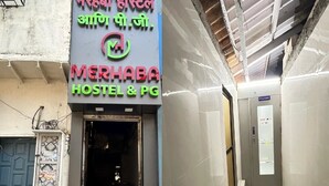 A hostel entrance with a sign in multiple languages, a motorcycle parked outside, and a corridor with a tiled floor. - Merhaba Hostel And PG (Mumbai)