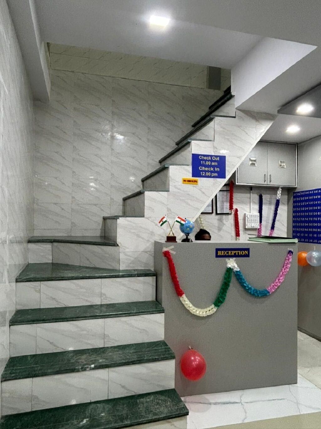 Un escalier en marbre mène à un espace d’accueil où un panneau indique les heures d’arrivée et de départ.