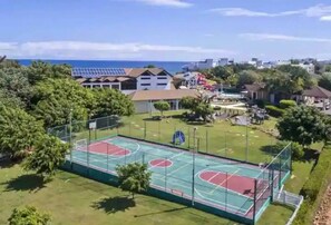 An outdoor basketball court surrounded by greenery and buildings, with a clear view of the ocean in the background. - Villa Ocean Dream 3BR Oasis and Guesthouse (Sosúa)