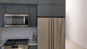 A modern kitchen with grey cabinets, a stainless steel microwave, a double oven, and a large refrigerator. - Perfect 7-bedroom house with stunning sunsets (Rosarito)