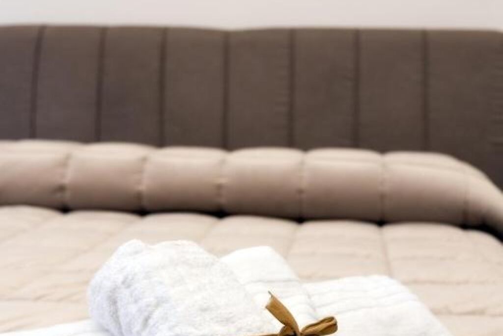 A beige sofa with a textured fabric and a brown cushion.