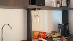 A compact kitchenette with a modern faucet, a coffee maker, and snack items like chips and cookies. - Deluxe Room with Balcony City View - Sofia and the City of Wonders (Napoli)