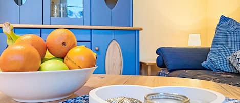 Een kamer met een blauwe kast, een fruitschaal, een hartvormig dienblad met sieraden, en een blauw gestreept vloerkleed.