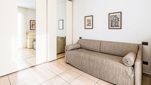 A modern living room with a sofa, a large mirror, and two framed pictures on the wall. - Lovely apartment for 4 guests with WIFI, A/C and balcony (Taggia)