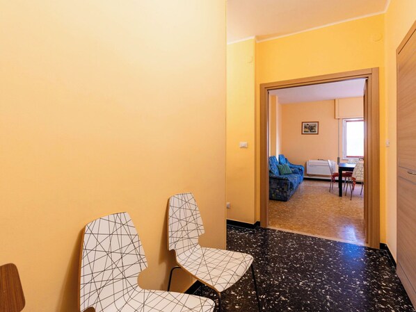 A hallway with a black and white patterned chair, a wooden door, and a view into a living area with a sofa and a table. - Beautiful apartment for 5 people with A/C, WIFI, TV and pets allowed (Diano Marina)