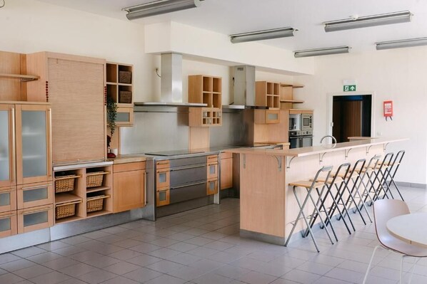 Une cuisine moderne avec des meubles en bois, des appareils électroménagers en acier inoxydable et un coin bar doté de chaises pliantes.