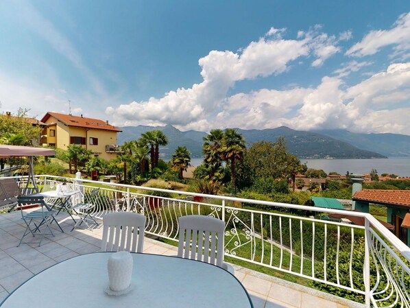 Eine Terrasse mit rundem Tisch und Stühlen mit Blick auf einen See und Berge.