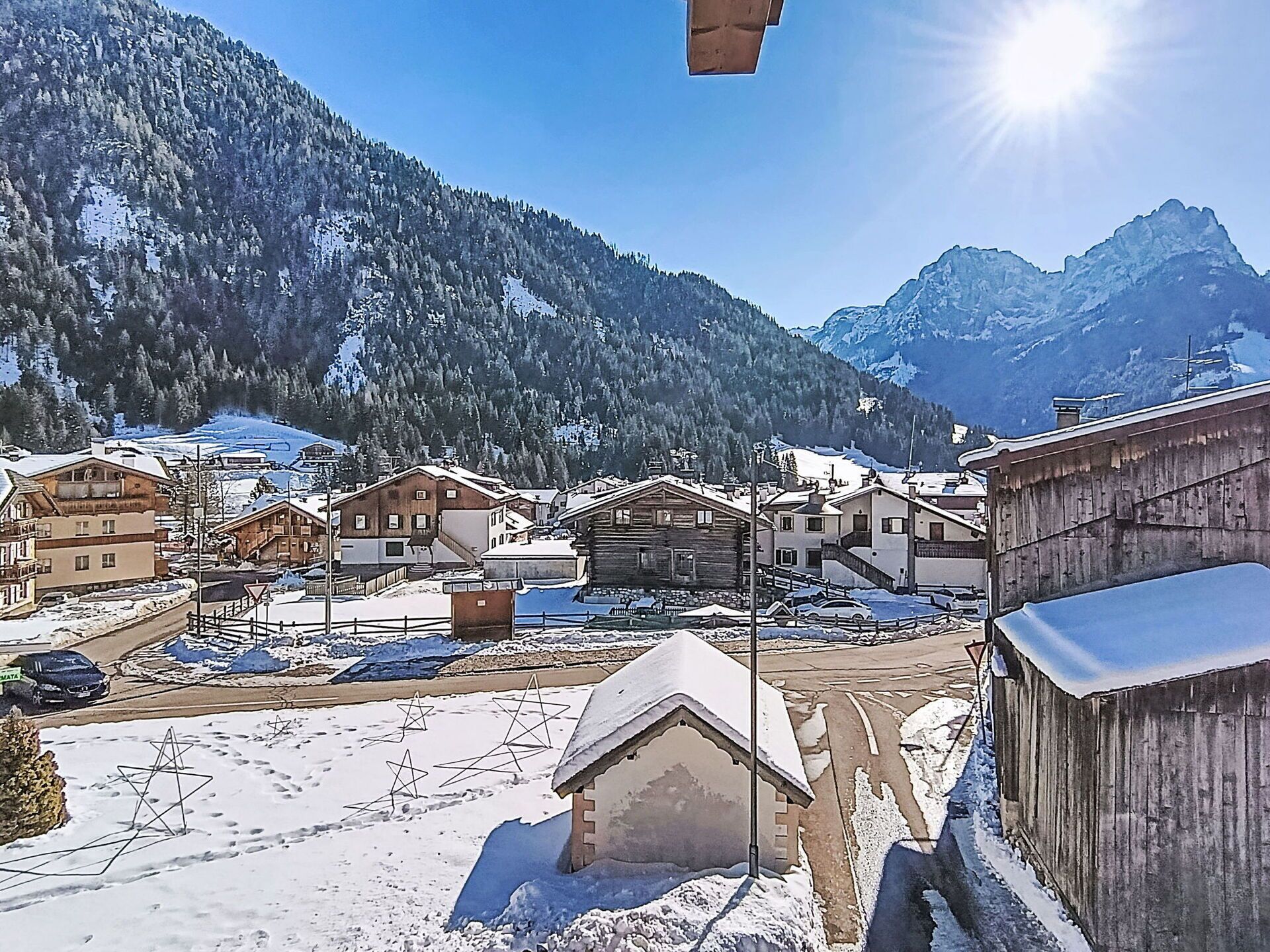 A snowy mountain village with traditional wooden houses, a clear sky, and a mountain backdrop.