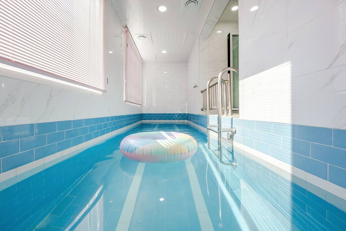 Ein Schwimmbecken mit einem bunten Luftring, gefliesten Wänden und einer Metallleiter.