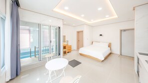 Ein modernes Hotelzimmer mit Balkon, einem Bett, einem Schreibtisch und einem kleinen Tisch.