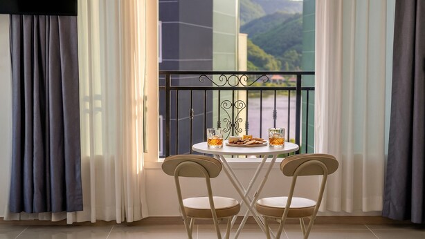 Un balcon avec deux chaises, une table et un verre de whisky.