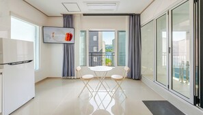 Ein modernes Apartment mit Küche, Essbereich und großen Schiebeglastüren zum Balkon.