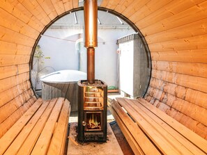 A wood-burning stove in a circular room with wooden benches.