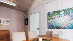 A conference room with a wooden table, chairs, a whiteboard, and a painting on the wall.