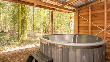 Un jacuzzi en una cabaña de madera con vista al bosque.
