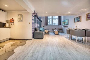 A modern living room with a sofa, a dining table, and a kitchen area. - Premium Central Liverpool Apartment | Sleeps 4 (Liverpool)