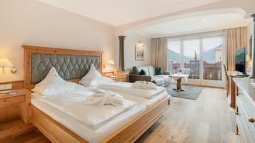 Una habitación de hotel con una cama grande, un sofá, un televisor y vistas a las montañas.