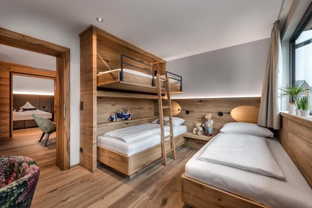 Habitación de hotel moderna con una cama nido, un escritorio, una silla y una ventana con cortinas.