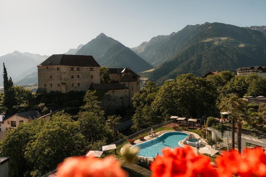 Un grand bâtiment doté d’une piscine, entouré d’une végétation luxuriante et avec des montagnes en toile de fond.