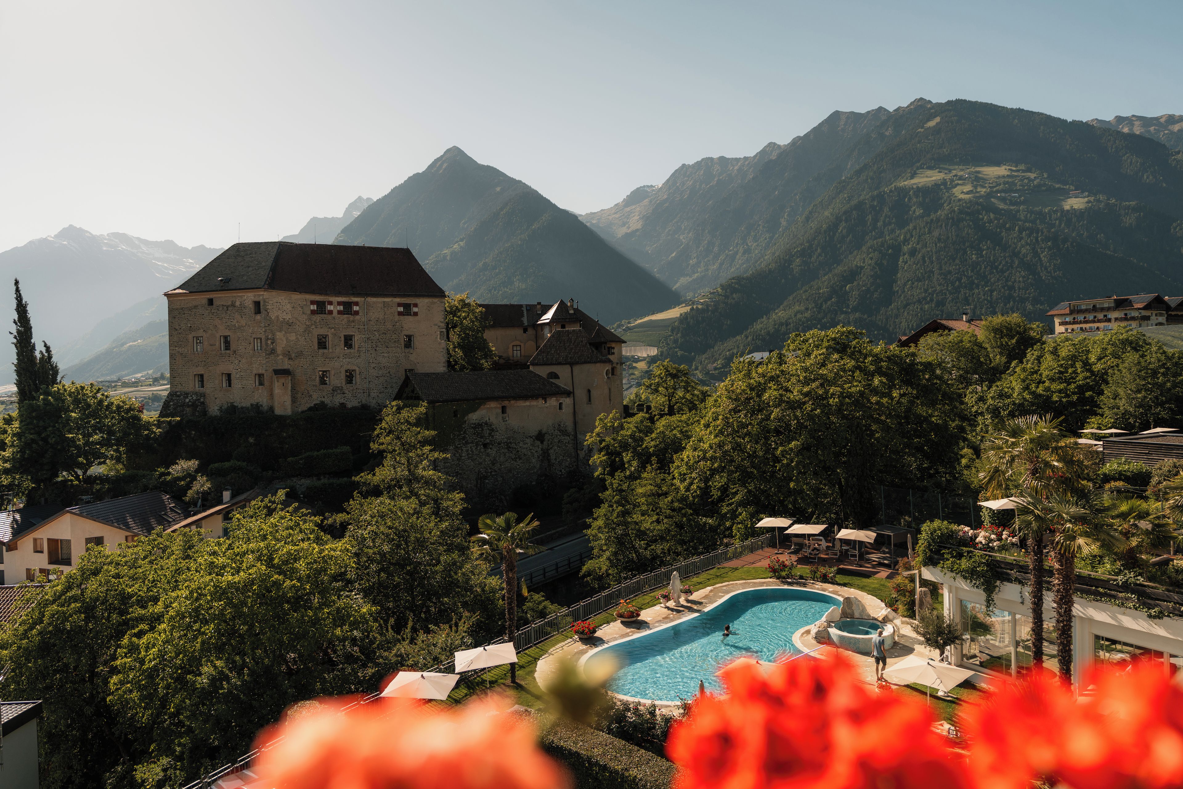 Un grande edificio con piscina circondato da vegetazione rigogliosa e montagne sullo sfondo.