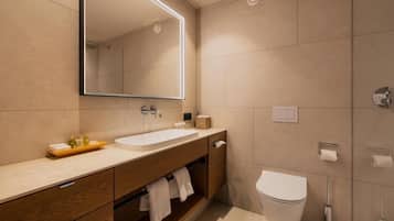 Uma casa de banho moderna com um espelho grande, uma pia, uma sanita e um porta-toalhas.