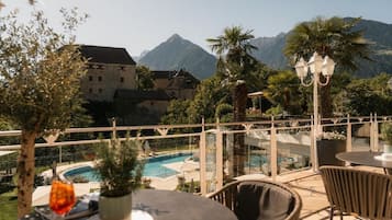 Um terraço com piscina, área de estar ao ar livre e vista para as montanhas.