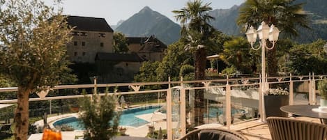 Une terrasse avec piscine, des sièges extérieurs et une vue sur les montagnes.