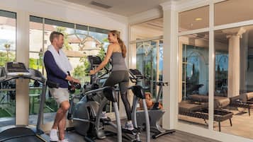 A gym with treadmills and weights, large windows, and a view of the outdoors.