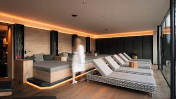 Un spa moderno con suelo de madera, una cama grande y una fila de sillones reclinables.