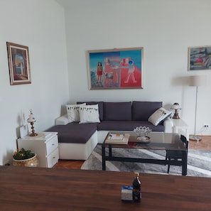 A living room with a sofa, a coffee table, a lamp, and a painting on the wall. - Royal Balcony al Mare (Rovinj)