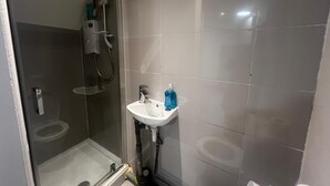Un baño moderno con cabina de ducha de vidrio, un lavabo blanco y un inodoro.
