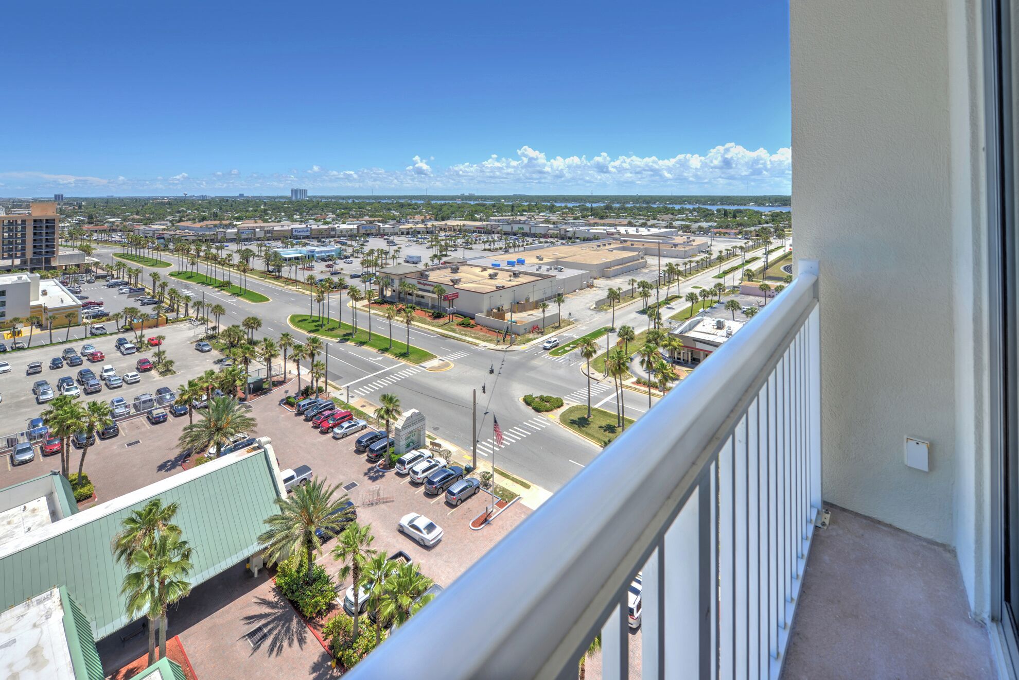 A high-rise building with a view of a parking lot and a commercial area.