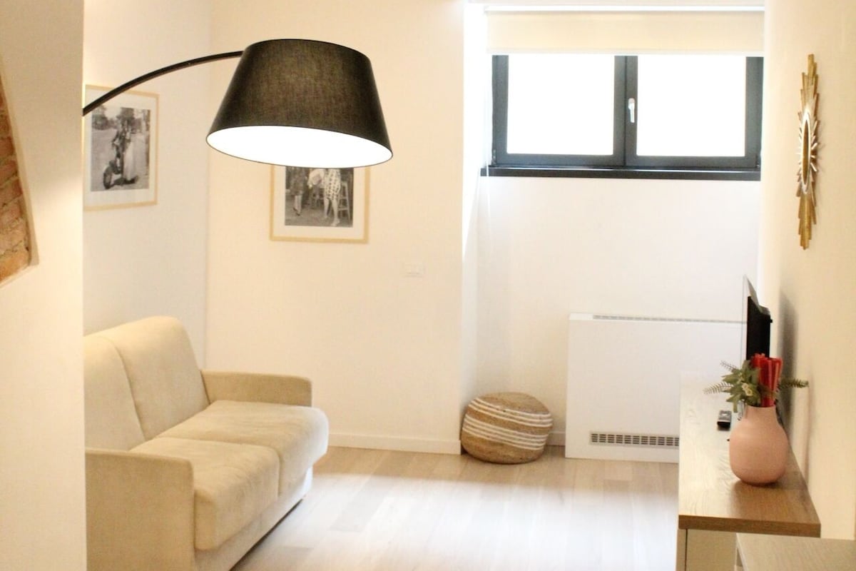 Uma sala de estar com sofá, abajur, lareira e janela.