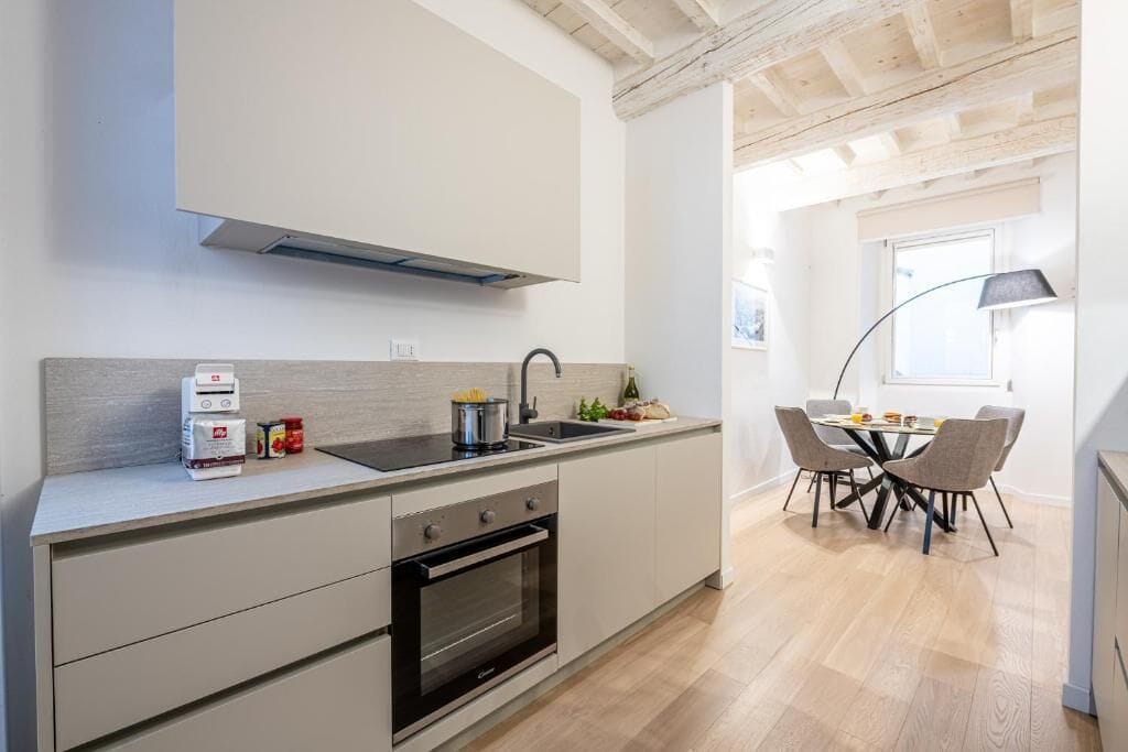 Uma cozinha moderna com forno embutido, pia e área de jantar com mesa e cadeiras.
