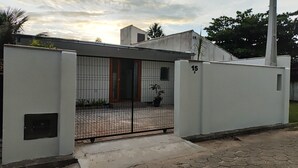 Um imóvel residencial com portão, entrada com azulejos, uma pequena planta em vaso e o número 15 visível.