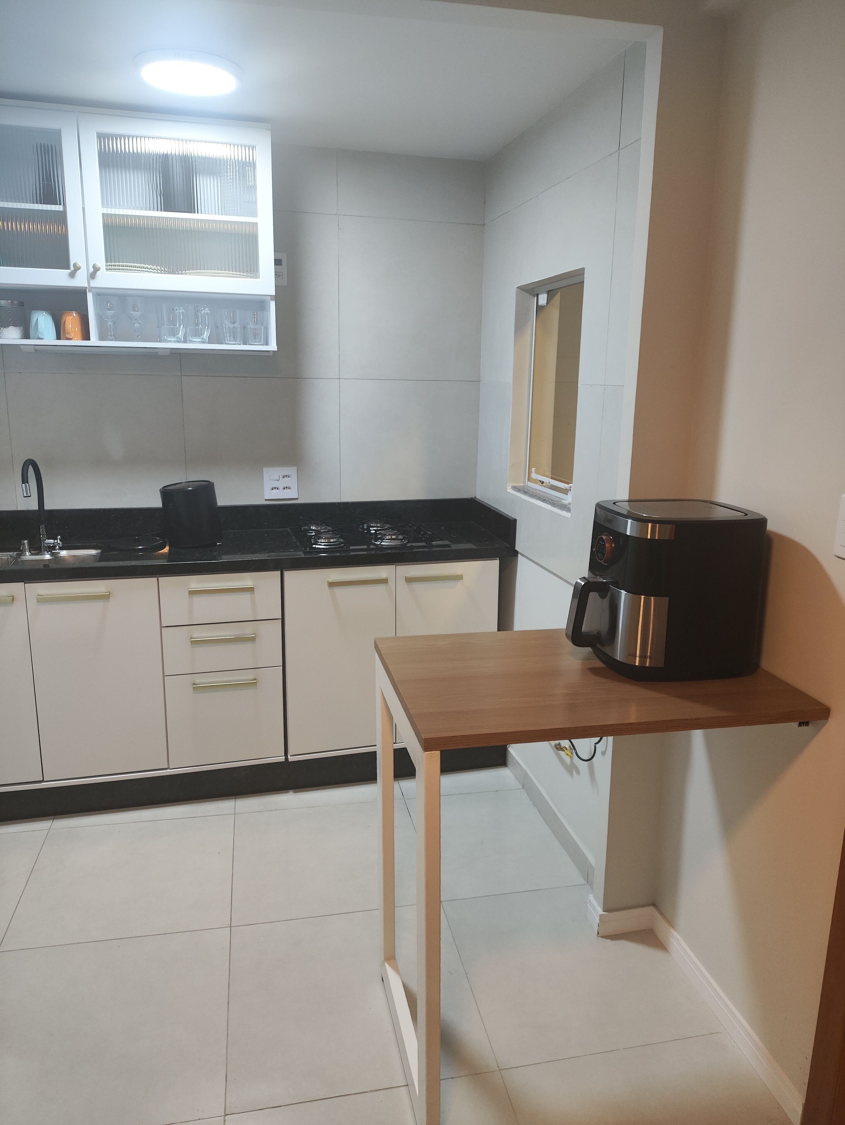 A small kitchen with white cabinets, a black countertop, and a coffee maker on a wooden table.