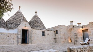 A stone building with conical roofs, a stone staircase, and a chair. - Authentic Trulli Stay with Private Pool and Panoramic Views | Itria Valley (Martina Franca)